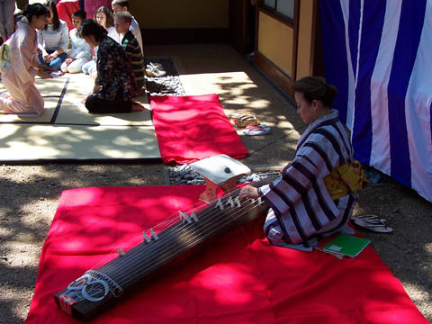 A Japanese lady in traditional kimono dress plays the Japanese harp.